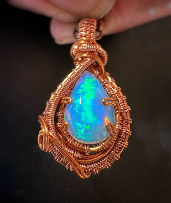 Ethiopian Witte Opaal pendant wrapped in intricate copper wire craftsmanship.