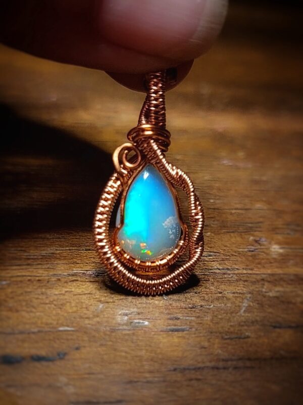 Opal pendant with copper wire wrapping, showcasing a vibrant blue and green play of colors.