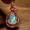 Pendant with opalescent gemstone and copper wire wrapping.