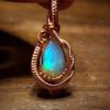 Opal pendant with copper wire wrapping, showcasing vibrant blue and green hues.
