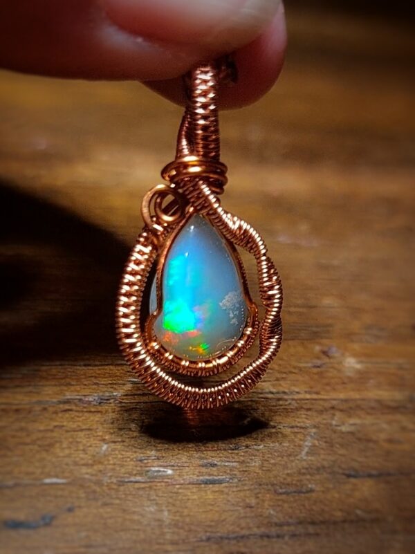 Opal pendant with copper wire wrapping, showcasing vibrant blue and green hues.